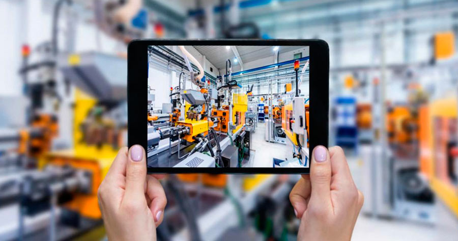 mãos segurando um tablet com imagem de máquinas de produção industrial